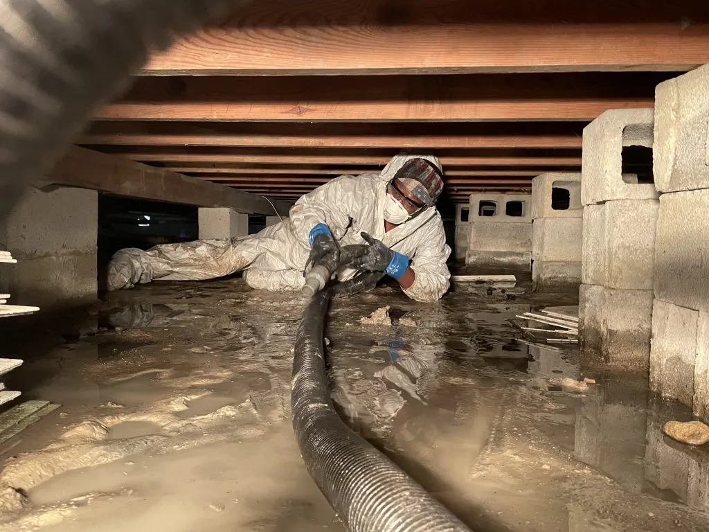 Crawlspace Technician Removing Standing Water From a Flooded Crawlspace